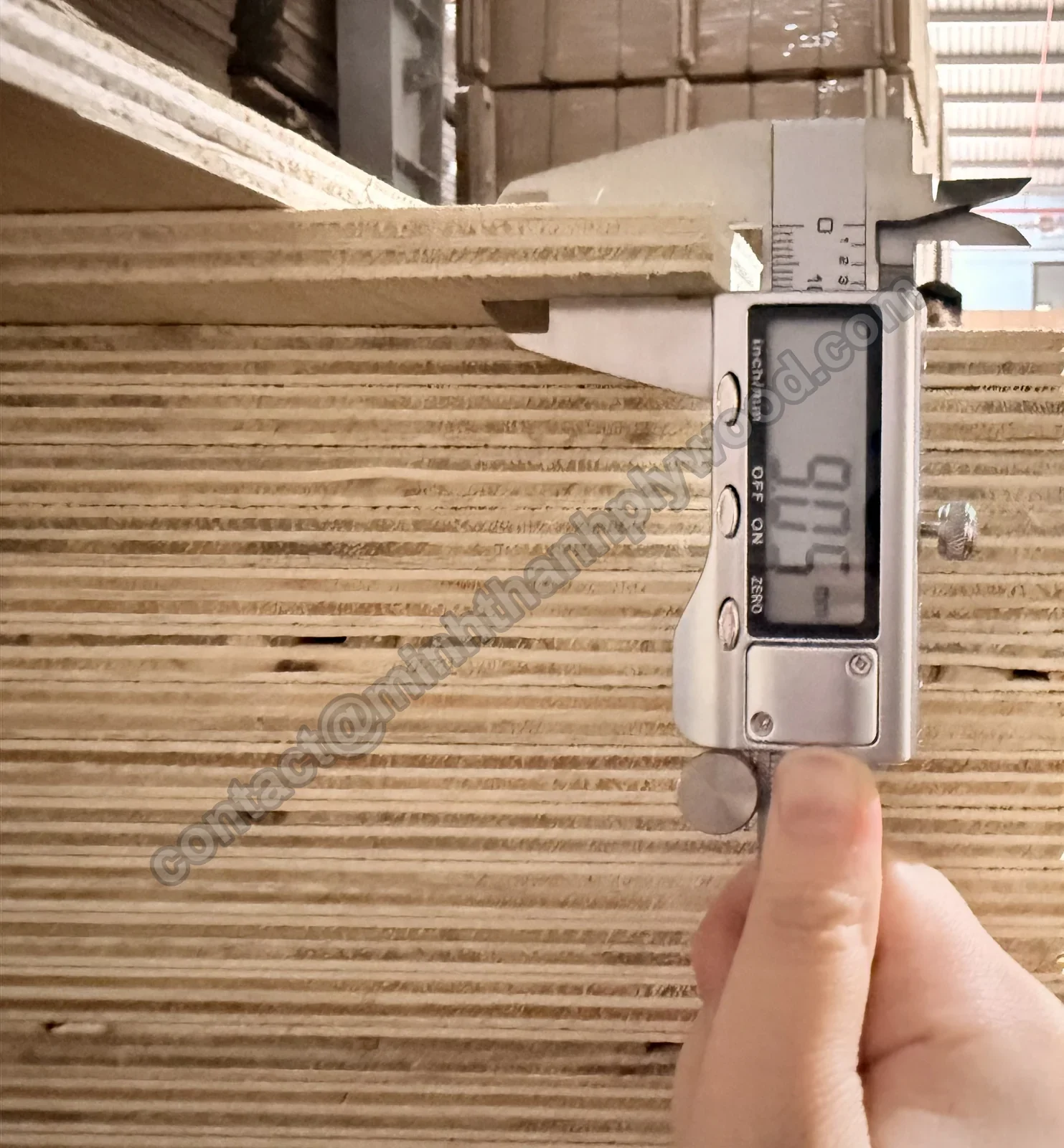 Een digitale schuifmaat op een multiplexpaneel van 9 mm toont 9,05 mm, met dunne stapellagen erachter