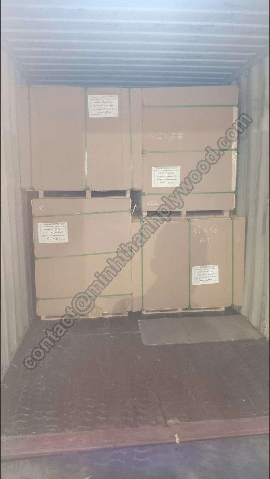 In karton verpakte multiplexpakketten op pallets, twee hoog in een container, met groene banden en labels