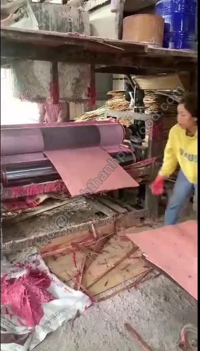 Opérateur introduisant un placage d’âme teinté rouge dans les rouleaux de l’encolleuse