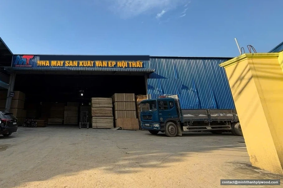 Poptávka překližky: kde vzniká vaše cenová nabídka překližky: pohled na továrnu Minh Thanh Plywood v Ha Hoa, provincie Phu Tho, s balíky překližky a nákladním autem na dvoře