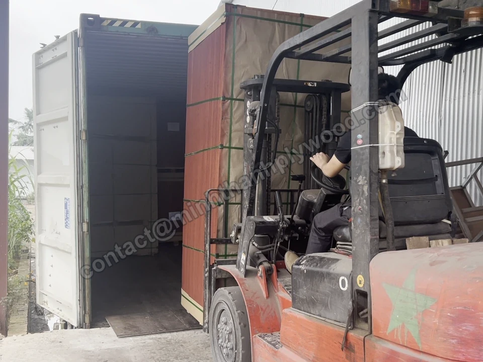 Gaffeltruck placerer en krydsfiner-pakke inde i en container
