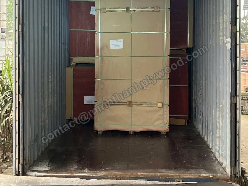 Cardboard-wrapped plywood packs loaded inside a shipping container