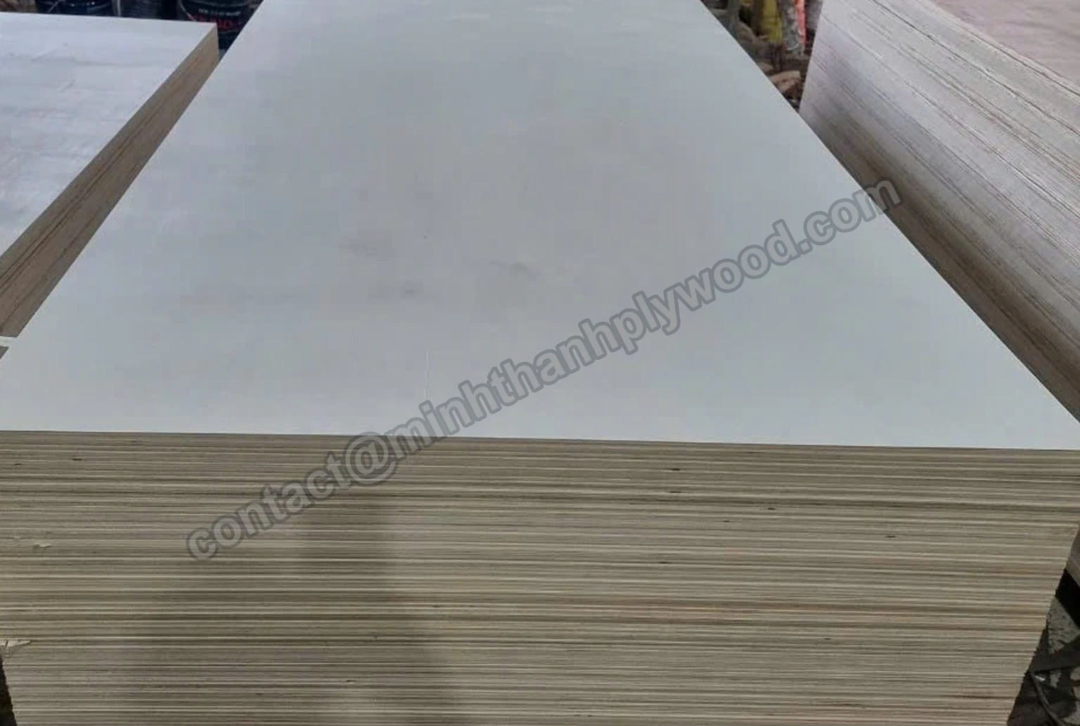Stack of finished white-faced plywood panels showing the top face and layered edge