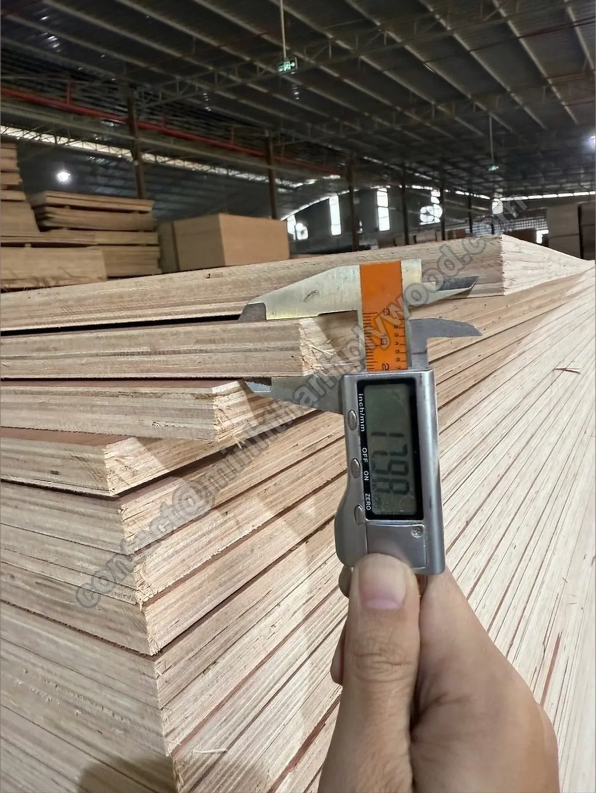 Digital caliper reading 17.98 mm on an 18 mm panel at the end of the plywood manufacturing process