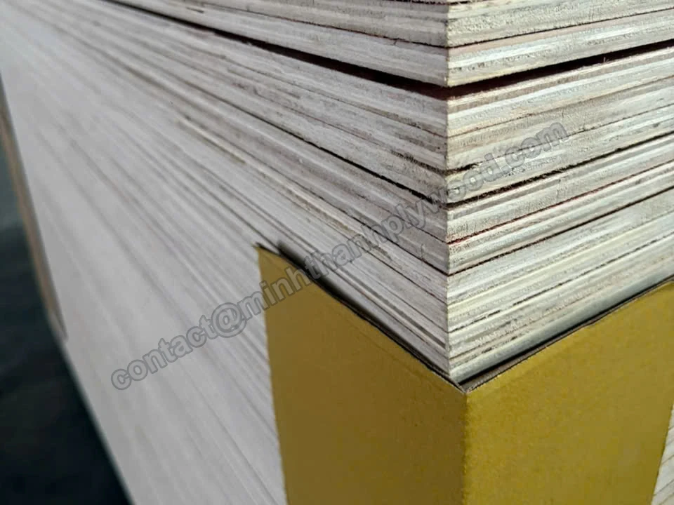 Yellow corner guard on the corner of a plywood stack with layered sheet edges
