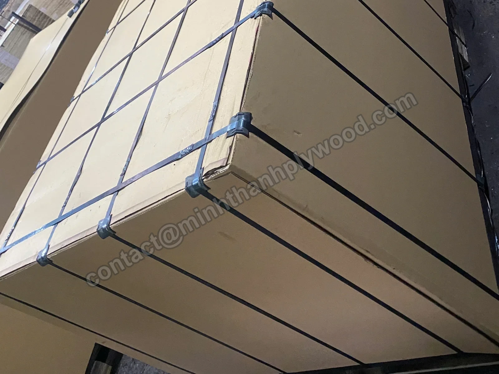 Steel straps with metal seals crossing the cardboard-covered top of a plywood export pack