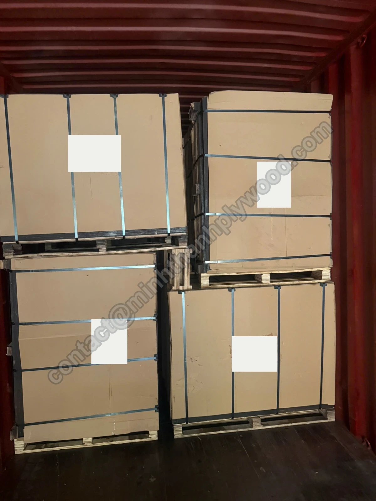 Cardboard-covered plywood packs with steel straps and labels on pallets inside a shipping container