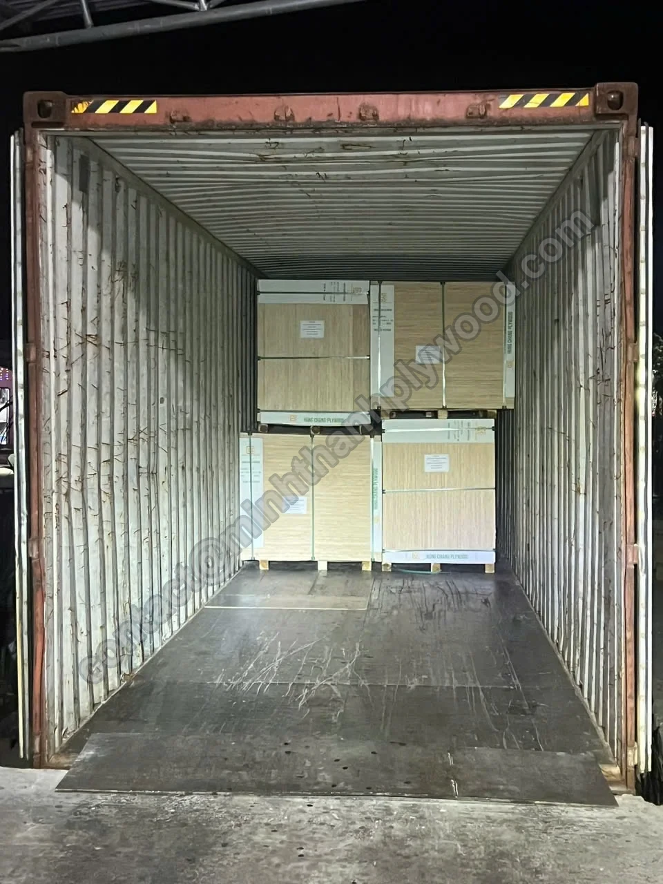 Shipping container loaded with four cardboard-covered plywood packs