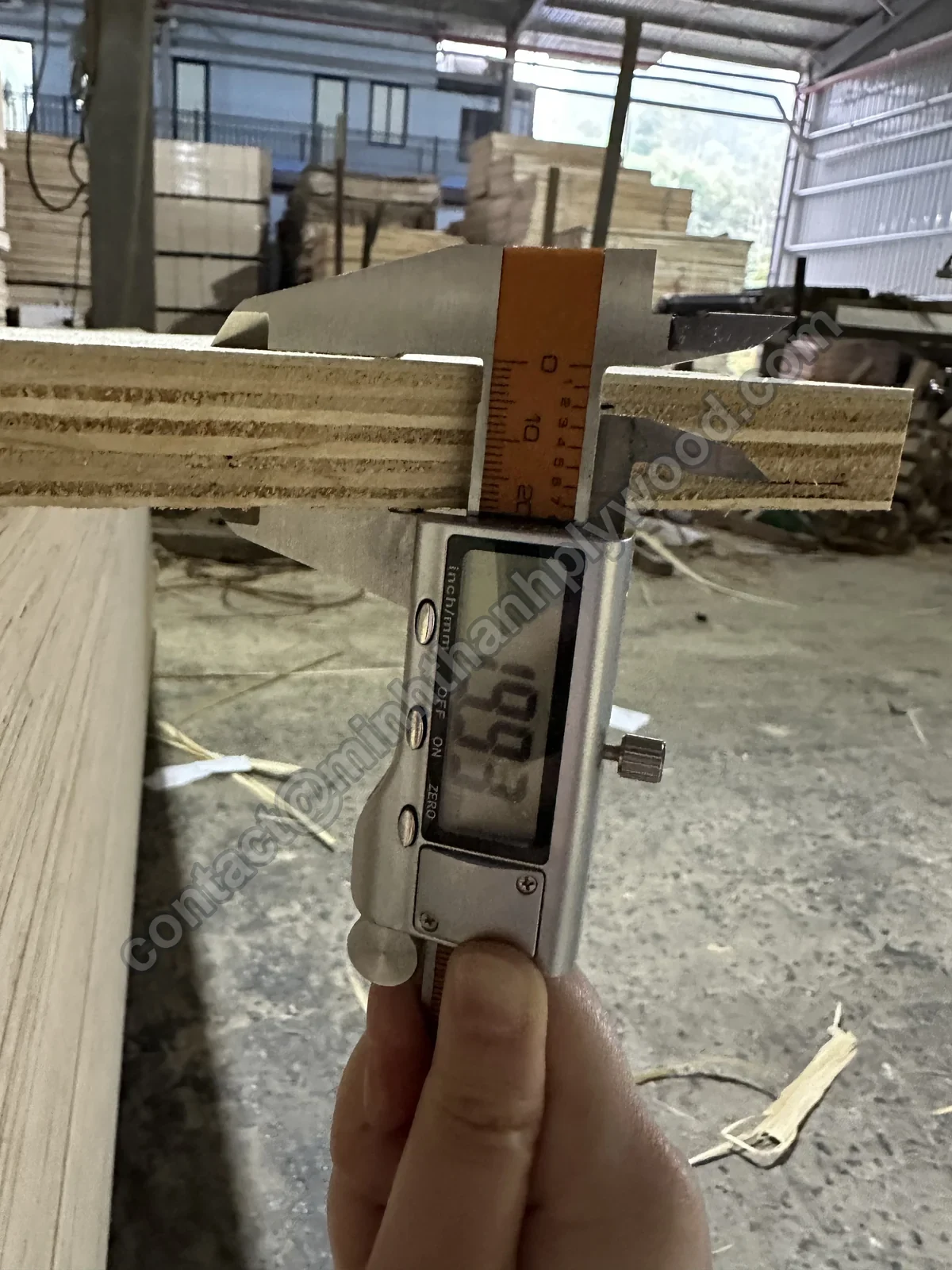 Digital caliper reading the thickness of a 20 mm furniture plywood panel