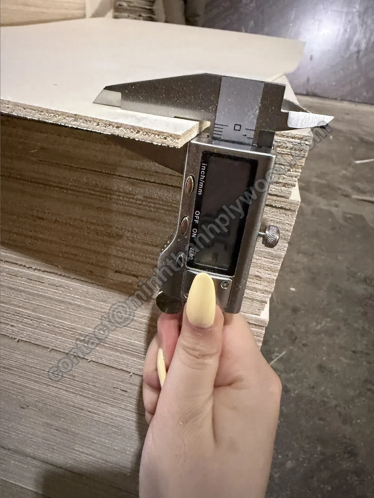 Digital caliper measuring a 4 mm poplar-faced plywood panel on a stack