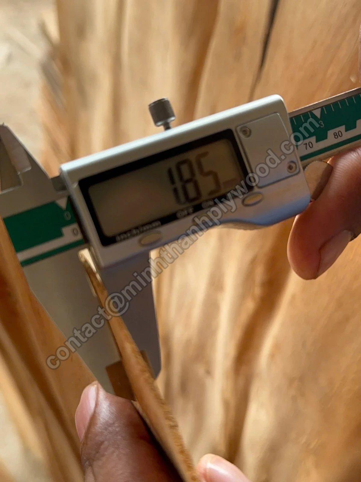 Digital caliper reading 1.85 mm on a hand-held core veneer sheet